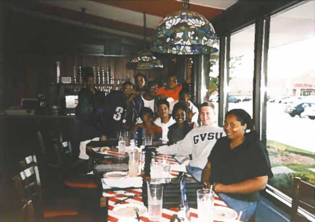 Students sitting at a lunch table smiling at camera